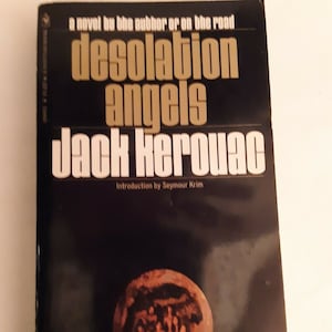 May include: A black and gold paperback book cover with the title "Desolation Angels" by Jack Kerouac. The cover features a small illustration of a group of people in a circle.