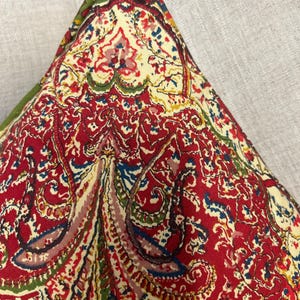 May include: Red, green and blue paisley patterned throw pillow with a cream background.
