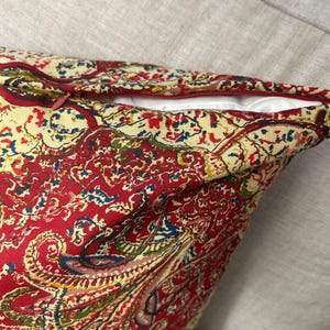 May include: Red paisley patterned cushion with a zip closure.