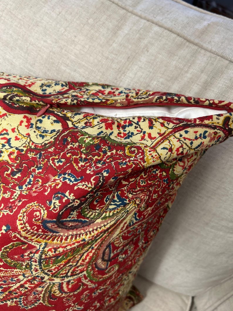 May include: Red paisley patterned cushion with a zip closure.