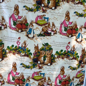 May include: White fabric featuring a repeating pattern of rabbits in a garden setting. The illustrations include rabbits in various outfits, with text in cursive. The color palette includes pink, red, blue, and brown.