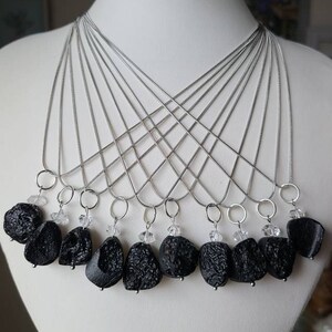 May include: A set of ten necklaces with black lava rock pendants and clear crystal accents. Each necklace features a silver chain.