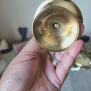Pu&ograve; includere: Un portacandele vintage in ottone con una base ampia e circolare e una parte superiore leggermente svasata. L'ottone ha una calda tonalit&agrave; dorata e la base mostra segni di et&agrave; e utilizzo. Il portacandele &egrave; progettato per contenere una singola candela.