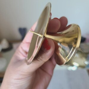 Pu&ograve; includere: Un portacandele color oro con una parte superiore ampia e piatta e una base svasata. Il supporto &egrave; in metallo e ha una finitura lucida. Il design &egrave; semplice ed elegante, adatto a vari stili di arredamento.