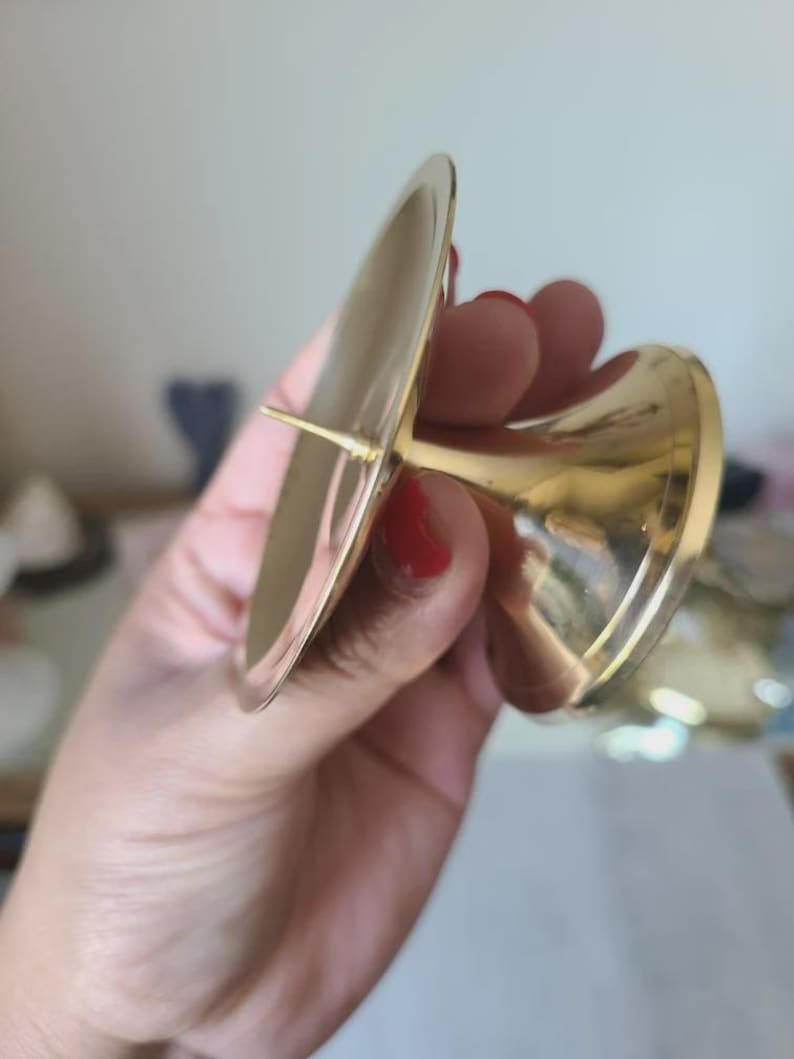 Pu&ograve; includere: Un portacandele color oro con una parte superiore ampia e piatta e una base svasata. Il supporto &egrave; in metallo e ha una finitura lucida. Il design &egrave; semplice ed elegante, adatto a vari stili di arredamento.