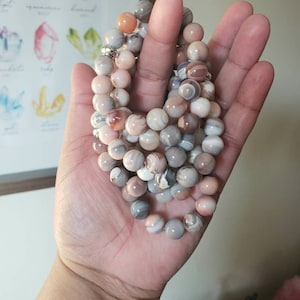 Op de afbeelding: Een meerstrengige armband gemaakt van agaat kralen in tinten roze, bruin en wit. De kralen zijn rond en hebben een natuurlijke, gepolijste afwerking.