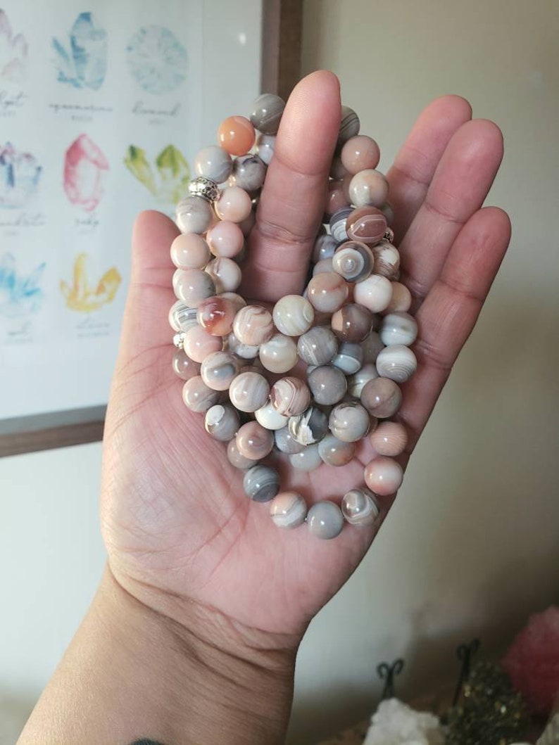 Op de afbeelding: Een meerstrengige armband gemaakt van agaat kralen in tinten roze, bruin en wit. De kralen zijn rond en hebben een natuurlijke, gepolijste afwerking.