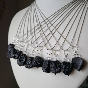 May include: A set of ten silver necklaces with black lava rock pendants and clear crystal accents.