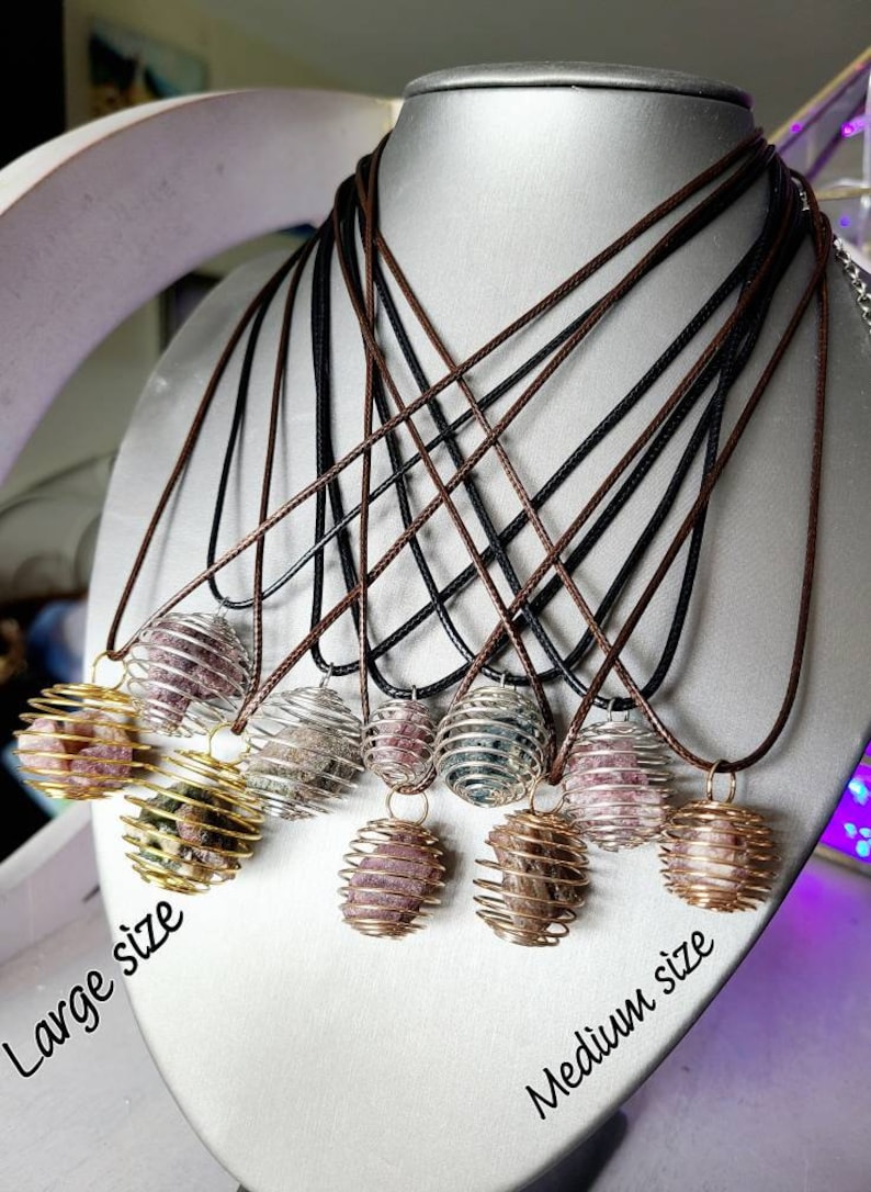 May include: A set of necklaces with caged crystal ball pendants. The pendants are available in two sizes, labeled "Large size" and "Medium size". The necklaces are made with brown and black cords.