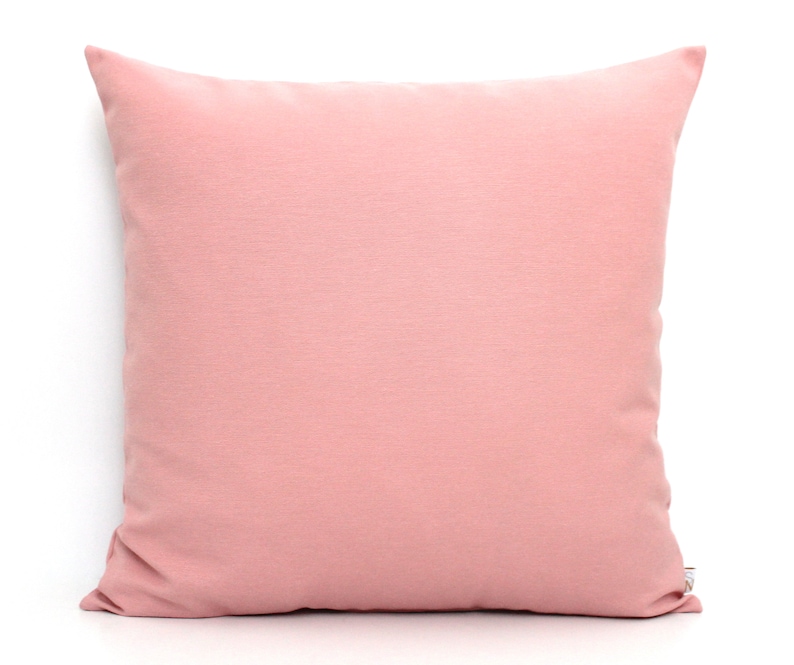 May include: A soft, blush pink throw pillow with a smooth, solid color. The pillow is made of a soft, comfortable fabric and is perfect for adding a touch of color to any room.