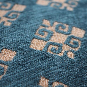 K&ouml;nnte beinhalten: Nahaufnahme eines blauen und beigen Stoffes mit Muster und texturierter Oberfl&auml;che. Der Stoff hat ein geometrisches Design mit sich wiederholenden Quadraten und Kreisen.