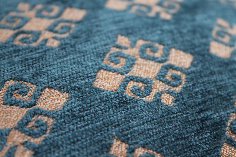 K&ouml;nnte beinhalten: Nahaufnahme eines blauen und beigen Stoffes mit Muster und texturierter Oberfl&auml;che. Der Stoff hat ein geometrisches Design mit sich wiederholenden Quadraten und Kreisen.