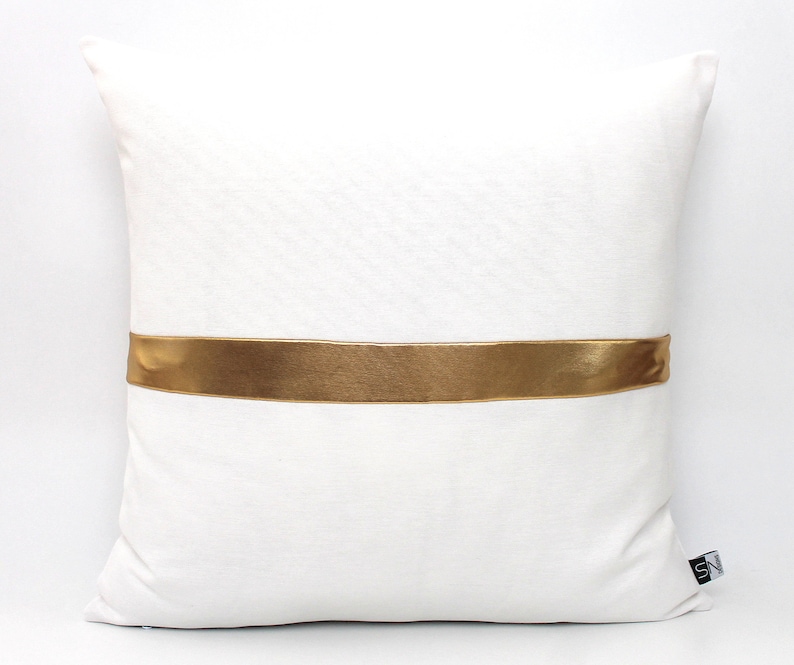 May include: White pillow with a gold satin ribbon across the center.