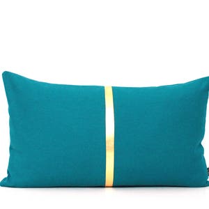 May include: Teal blue rectangular pillow with a gold stripe down the center.