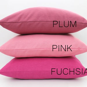 Puede incluir: Tres almohadas decorativas apiladas una encima de la otra. La almohada superior es de color ciruela, la almohada del medio es de color rosa y la almohada inferior es de color fucsia. Las almohadas est&aacute;n hechas de una tela suave y texturizada.