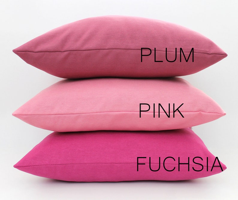 Puede incluir: Tres almohadas decorativas apiladas una encima de la otra. La almohada superior es de color ciruela, la almohada del medio es de color rosa y la almohada inferior es de color fucsia. Las almohadas est&aacute;n hechas de una tela suave y texturizada.
