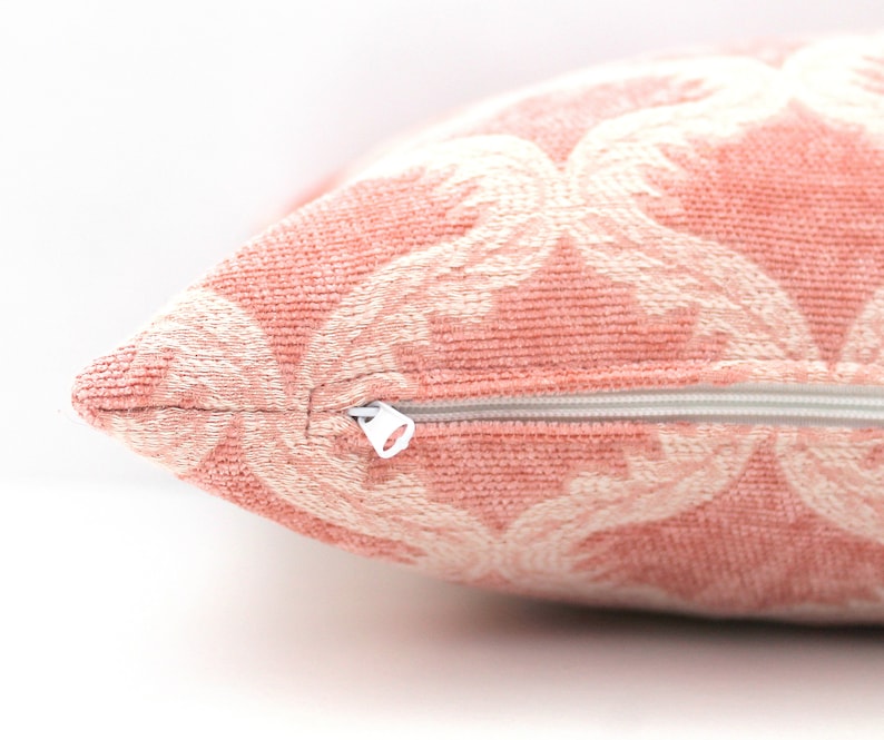 Pode incluir: Uma almofada rosa com um padr&atilde;o floral branco e um fecho de correr.