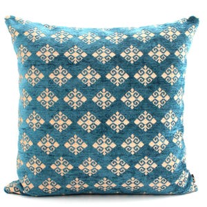 K&ouml;nnte beinhalten: Ein blaues Kissen mit einem cremefarbenen geometrischen Muster. Das Muster ist eine sich wiederholende Diamantform mit einem stilisierten floralen Design in jedem Diamanten.