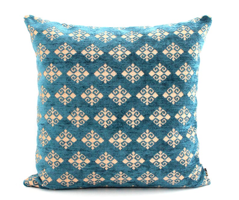 K&ouml;nnte beinhalten: Ein blaues Kissen mit einem cremefarbenen geometrischen Muster. Das Muster ist eine sich wiederholende Diamantform mit einem stilisierten floralen Design in jedem Diamanten.