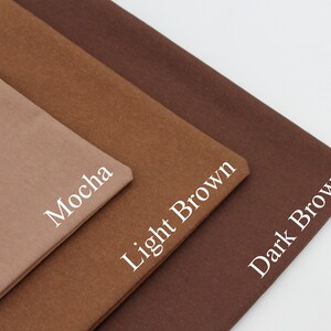 May include: Three fabric swatches in varying shades of brown are displayed. The swatches are labelled "Mocha", "Light Brown", and "Dark Brown" in white text. The fabrics are folded and arranged diagonally, highlighting the colour variations.