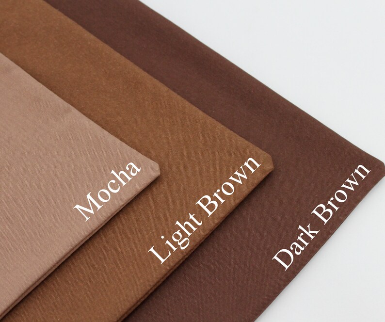 May include: Three fabric swatches in varying shades of brown are displayed. The swatches are labelled "Mocha", "Light Brown", and "Dark Brown" in white text. The fabrics are folded and arranged diagonally, highlighting the colour variations.