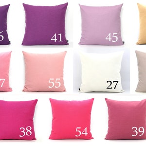 K&ouml;nnte beinhalten: Eine Sammlung quadratischer Kissen in verschiedenen unifarbenen Farben, darunter Lila, Rosa und Beige. Jedes Kissen hat eine wei&szlig;e Nummer aufgedruckt, die von 27 bis 55 reicht. Die Kissen sind in einem Raster angeordnet und zeigen eine Reihe von Farbt&ouml;nen.