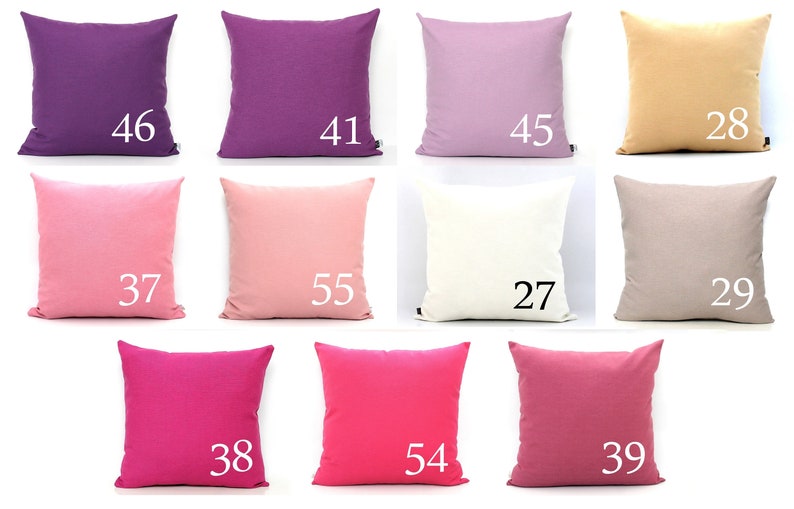 K&ouml;nnte beinhalten: Eine Sammlung quadratischer Kissen in verschiedenen unifarbenen Farben, darunter Lila, Rosa und Beige. Jedes Kissen hat eine wei&szlig;e Nummer aufgedruckt, die von 27 bis 55 reicht. Die Kissen sind in einem Raster angeordnet und zeigen eine Reihe von Farbt&ouml;nen.