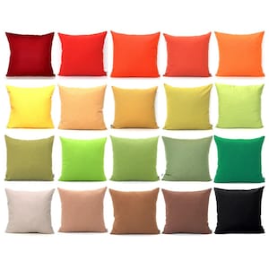 May include: A collection of twenty square throw pillows arranged in a grid, featuring a diverse spectrum of solid colors including shades of red, orange, yellow, green, brown, beige, and black, all with a consistent fabric texture.