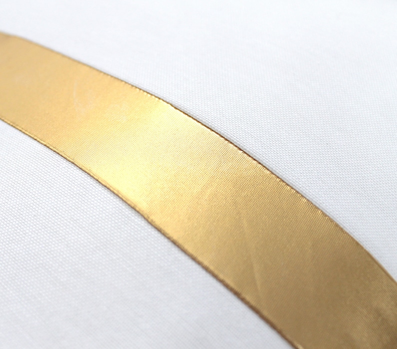 May include: A white pillow with a gold satin ribbon running diagonally across the front.