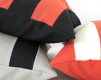 Funda de almohada bicolor en negro y crema: cojín decorativo de algodón resistente.