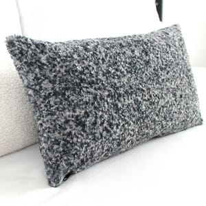 May include: A gray and white fluffy rectangular pillow with a zipper closure.