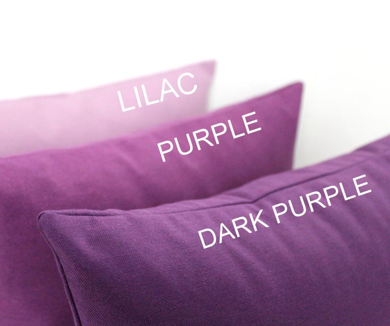 May include: Three rectangular cushions in shades of purple, from light lilac to dark purple. The text "LILAC", "PURPLE", and "DARK PURPLE" are printed on the cushions. The cushions are made of a solid-colored fabric.