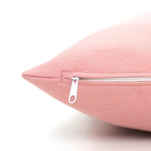 May include: A close-up of a pink pillow with a white zipper. The zipper is partially open, revealing the inside of the pillow.