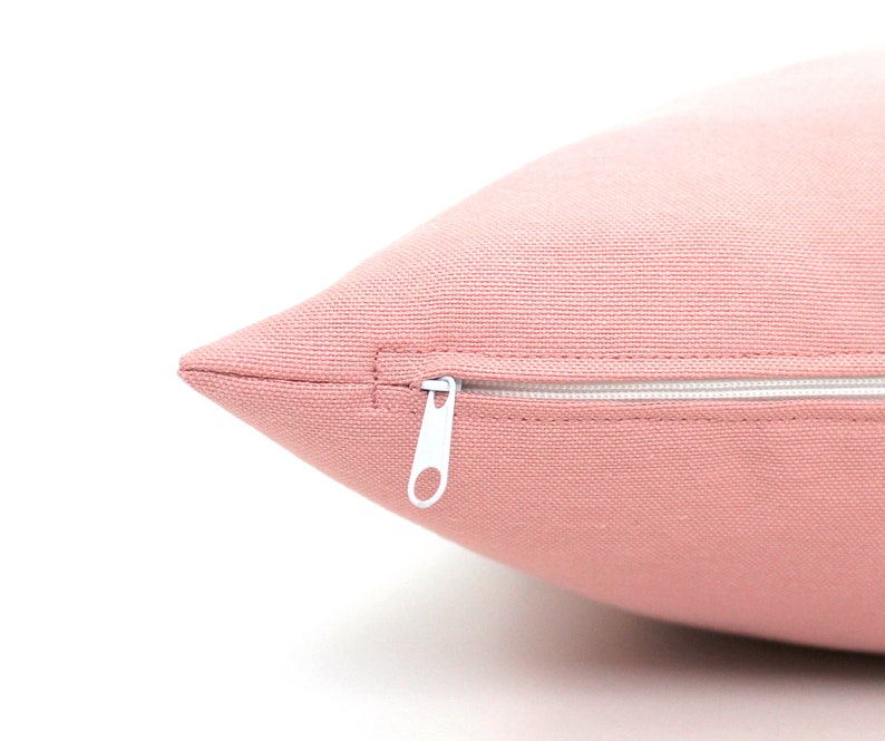 May include: A close-up of a pink pillow with a white zipper. The zipper is partially open, revealing the inside of the pillow.