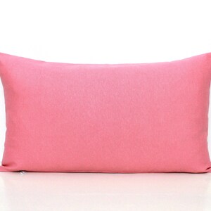 Puede incluir: Una almohada rectangular de color rosa s&oacute;lido con una textura lisa y uniforme.