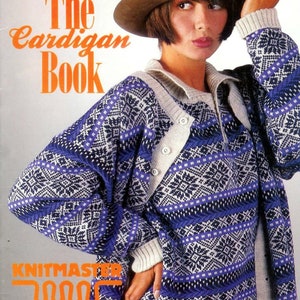 Puede incluir: Una portada de libro con una mujer que lleva un sombrero marrón y un cárdigan con estampado azul y blanco. El título del libro es "The Cardigan Book" y también se puede ver el texto "Knitmaster 1000 creative kone".