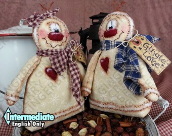 Può includere: Due bambole a forma di pupazzo di neve fatte a mano con corpi color crema, cuori rossi e sciarpe a quadri. Una bambola ha una sciarpa viola e bianca, l'altra blu e bianca. Ognuna ha un'etichetta con scritto "Gingie Love".