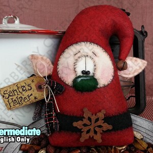 May include: A handmade Christmas decoration in the shape of Santa's helper. The red felt figure has a black belt with a snowflake, a green mouth, and a tag that reads "Santa's Helper".