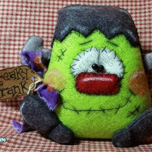 May include: A handmade Frankenstein's monster plush doll with a green body, black hair, and stitched features. The doll has a red mouth, white eyes, and a tag that reads "Freaky Frank". A fun Halloween decoration.