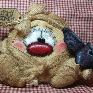 May include: A handcrafted burlap doll with a stitched face, red lips, and a black bat. The doll has a tag that reads "Mummy Dearest & Ozzy". The background is a red and white checkered pattern.