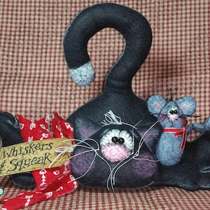 May include: A whimsical, handmade felt cat figurine in dark gray, with a curled tail and a gray and white tip. A gray mouse with a red ribbon sits on the cat. A tag reads "Whiskers & Squeak".
