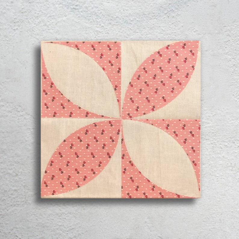 Puede incluir: Un bloque de colcha rosa y blanco con un dise&ntilde;o geom&eacute;trico. El bloque est&aacute; hecho de tela con un peque&ntilde;o patr&oacute;n floral rojo y blanco.