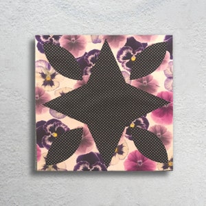 Puede incluir: Una estrella de color negro y blanco con lunares sobre un fondo blanco. La estrella est&aacute; hecha de papel y est&aacute; superpuesta a un collage de flores moradas y rosas.