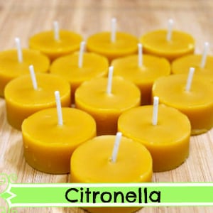 May include: A group of 15 yellow citronella tea light candles on a wooden surface.