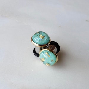 Aquamarine resin with gold and opalescent flakes in a gold bezeled setting plugs gauges 8g 6g 4g 2g 0g 00g 7/16” 1/2” 3mm-12mm