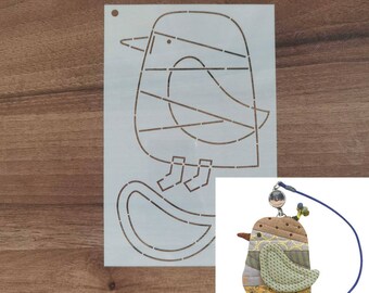 May include: A stencil featuring a bird design with a round body, a beak, and feet. The bird is sitting on a curved line. A small, colorful fabric bird ornament with a blue string is also shown.