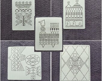 May include: Five white rectangular cards with intricate black geometric designs. Each card features a unique pattern of lines, dots, and shapes, creating a collection of abstract art. The cards are arranged on a textured, dark gray surface.