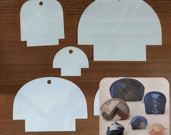 May include: A collection of white plastic sewing templates in various sizes, each with a rounded top and a rectangular base. A small hole is at the top of each template. A color image of finished coin purses is in the lower right corner.