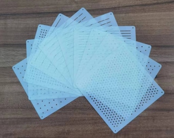 May include: A collection of clear, rectangular stencils with various patterns, including dots and lines. The stencils are arranged in a fan shape on a wooden surface, providing a variety of design options for crafts and art projects.