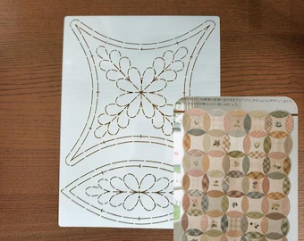 May include: A white quilting stencil with a floral design and a sample quilt pattern. The stencil features a large flower and leaf pattern. The sample quilt has a patchwork design with floral and leaf motifs.